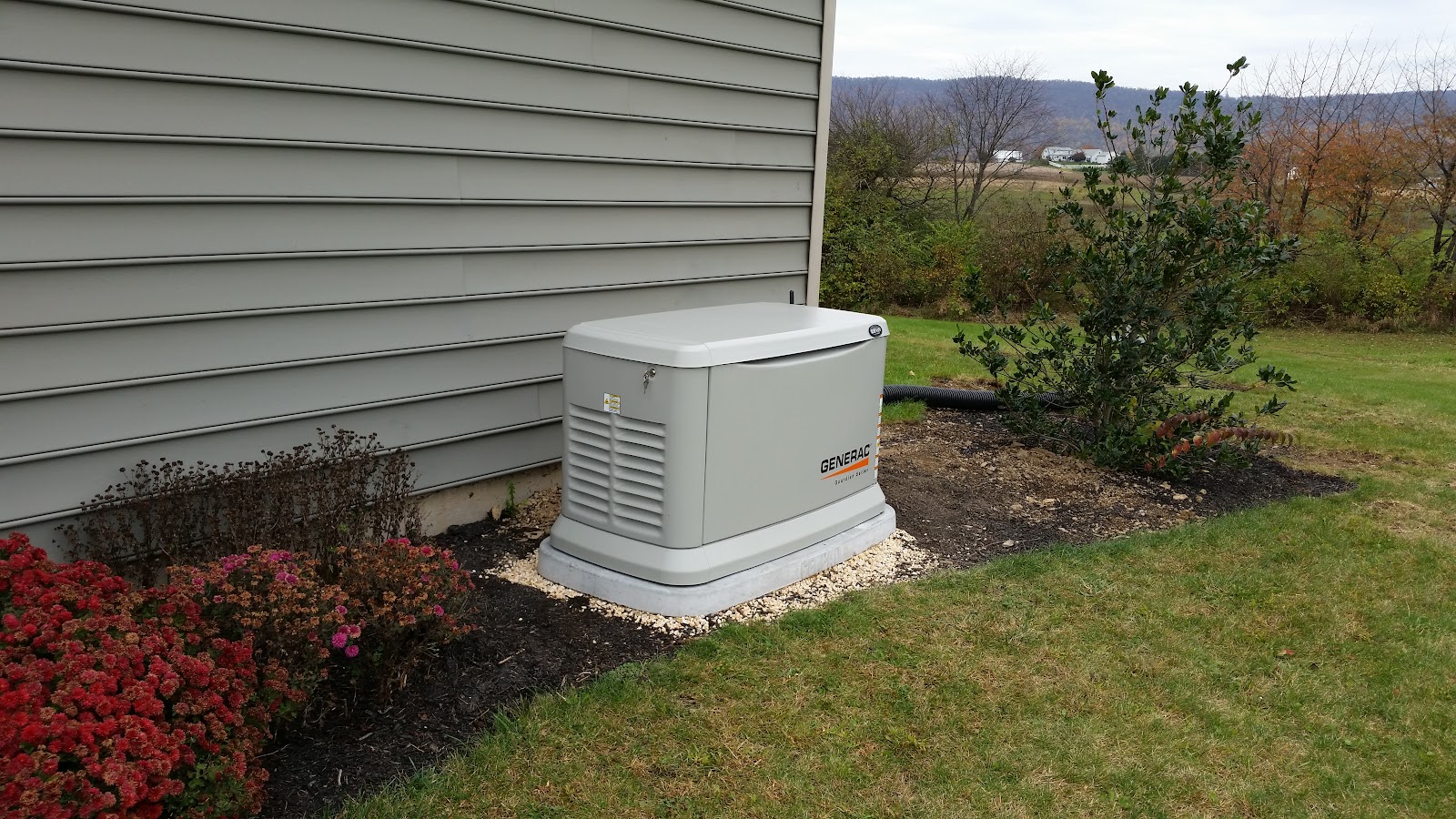 Air-cooled Generac standby generator on a pad beside a home